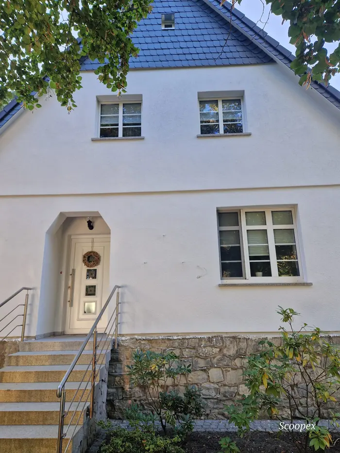 Eingangsseite eines Hauses in Rehbrücke mit hellem Putz und Natursteinsockel